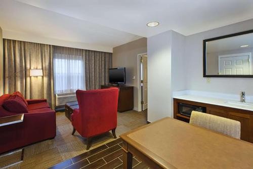 a living room with a red chair and a couch at Hampton Inn & Suites Providence-Warwick Airport in Warwick