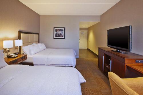 a hotel room with two beds and a flat screen tv at Hampton Inn & Suites Providence-Warwick Airport in Warwick