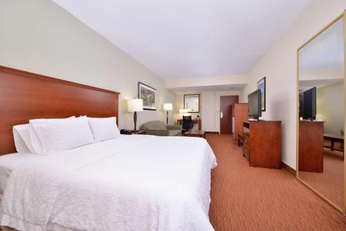 a hotel room with a white bed and a flat screen tv at Hampton Inn Waynesboro/Stuarts Draft in Fishersville