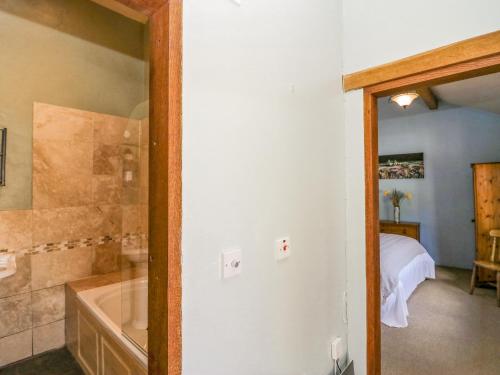 a bathroom with a tub and a bedroom with a bed at Egg Pudding Stone in Grange Over Sands
