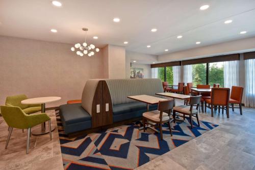 una sala d'attesa con tavoli, sedie e un divano di Hampton Inn Potomac Mills Woodbridge a Woodbridge