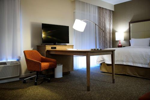 a hotel room with a desk with a television and a bed at Hampton Inn & Suites Truro, NS in Truro