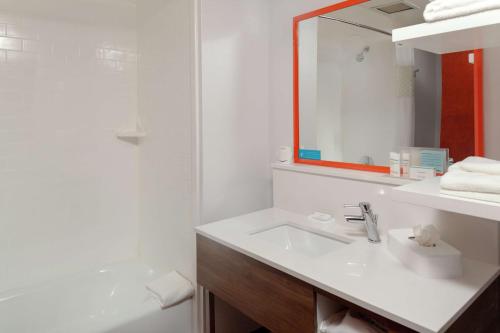 a bathroom with a sink and a mirror and a tub at Hampton Inn Woodbridge in Woodbridge