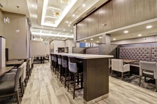 a restaurant with a bar with chairs and tables at Hampton Inn St. Catharines Niagara in St. Catharines