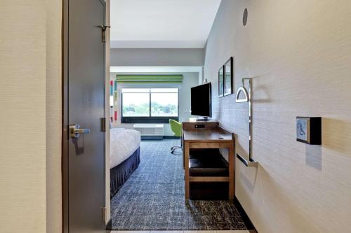 a room with a bed and a desk with a television at Hampton Inn St. Catharines Niagara in St. Catharines