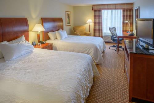 a hotel room with two beds and a flat screen tv at Hilton Garden Inn Joplin in Joplin