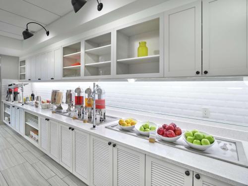 a kitchen with white cabinets and bowls of fruit on the counter at DoubleTree by Hilton Edmonton Downtown in Edmonton