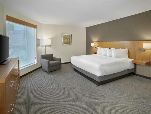 a hotel room with a bed and a chair and a television at DoubleTree by Hilton Edmonton Downtown in Edmonton