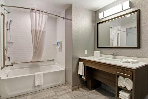 Home2 Suites By Hilton Edmonton South في إيدمونتون: حمام مع حوض ومغسلة ومرآة