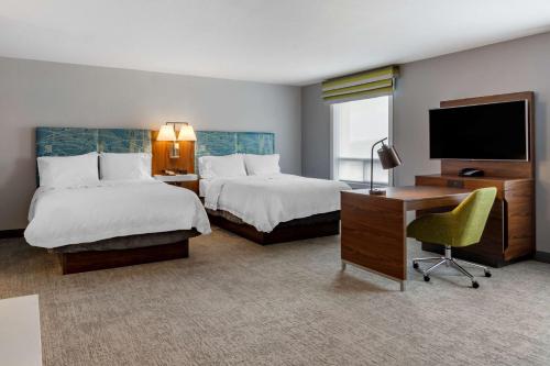 a hotel room with two beds and a desk and a television at Hampton Inn & Suites Edmonton/West in Edmonton