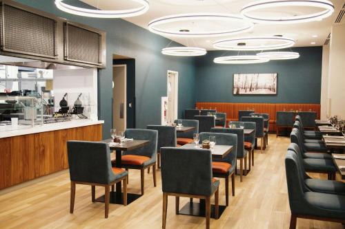une salle à manger avec des tables et des chaises ainsi qu'un bar dans l'établissement Hilton Garden Inn Fredericton, à Fredericton