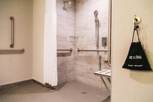a bathroom with a shower with a bag on the door at Hilton Garden Inn Fredericton in Fredericton