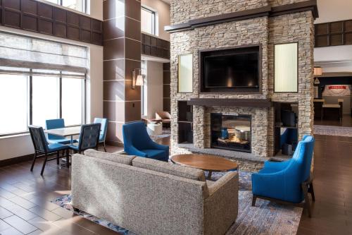 a living room with a fireplace and blue chairs at Hampton Inn & Suites by Hilton Dartmouth - Halifax in Halifax