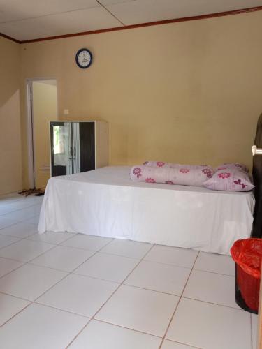 - une chambre avec un grand lit et une horloge murale dans l'établissement SegeHomestay, à Rinondoran