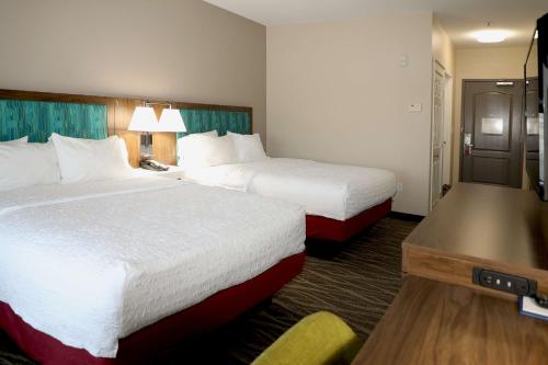 a hotel room with two beds and a desk at Hampton Inn Ellensburg in Ellensburg