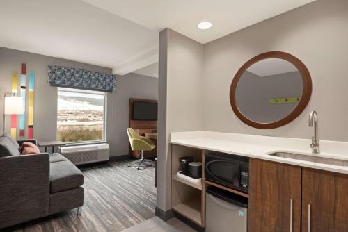 Hampton Inn & Suites Kelowna, British Columbia, Canada في كيلونا: غرفة في الفندق مع أريكة ومغسلة ومرآة