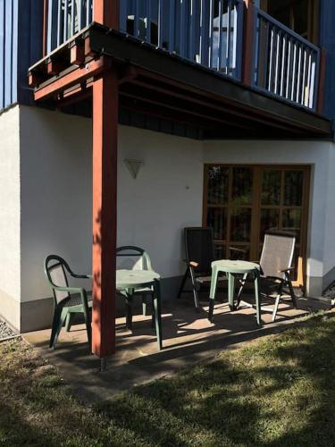 un patio con sillas y mesas bajo un balcón. en Idyllische Ferienwohnung am See, en Rötz
