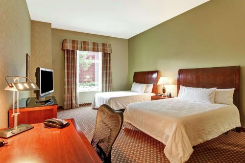 a hotel room with two beds and a desk at Hilton Garden Inn Ottawa Airport in Ottawa