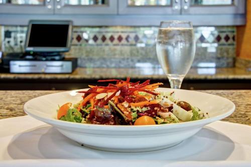 a salad in a white bowl next to a glass of water at Hilton Garden Inn Ottawa Airport in Ottawa