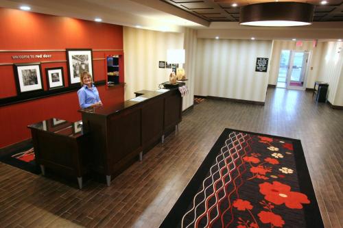 a lobby with a woman standing at a reception desk at Hampton Inn & Suites Red Deer in Red Deer