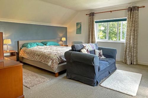 a bedroom with a bed and a couch and a window at Maesyfelin Isaf B&B in Llanybydder