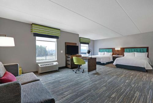 a hotel room with two beds and a couch at Hampton Inn Peterborough in Peterborough