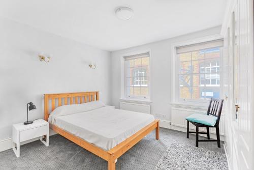 a white bedroom with a bed and a chair at Charming 4 bed town house with roof terrace in London