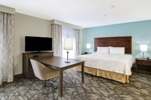 a hotel room with a bed and a desk and a television at Hampton Inn & Suites Saint John in Saint John