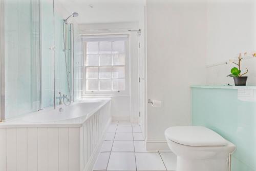 een witte badkamer met een bad en een toilet bij Charming 4 bed town house with roof terrace in Londen