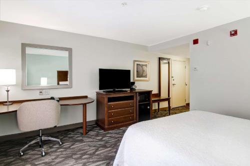 a hotel room with a bed and a desk and a television at Hampton Inn & Suites Saint John in Saint John