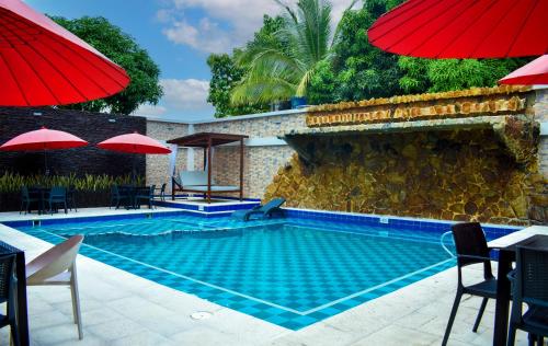 a swimming pool with chairs and umbrellas next to a building at Hotel Punta Arena Spa Boutique in Arauca