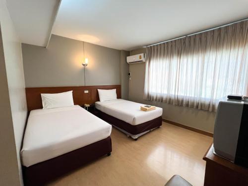 a hotel room with two beds and a television at Srivichai Hotel in Nakhon Ratchasima