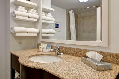 La salle de bains est pourvue d'un lavabo, d'un miroir et de serviettes. dans l'établissement Hampton Inn & Suites Saint John, à Saint-Jean