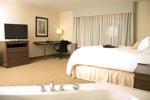 a hotel room with a bed and a sink and a television at Hampton Inn & Suites Saint John in Saint John
