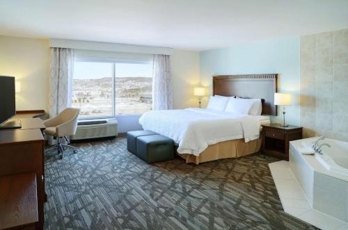 Habitación de hotel con cama, bañera y ventana en Hampton Inn & Suites Saint John, en Saint John