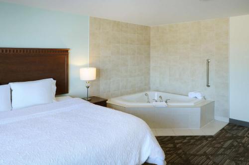 a hotel room with a bed and a bath tub at Hampton Inn & Suites Saint John in Saint John