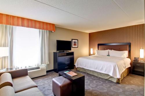 Homewood Suites by Hilton Toronto-Ajax في أجاكس: غرفه فندقيه بسرير واريكه