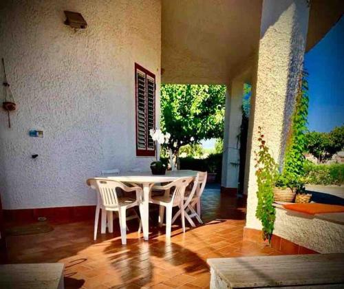 Un comedor con una mesa y sillas blancas. en Villa Anna - Bifamiliare sul mare, en Torregrotta