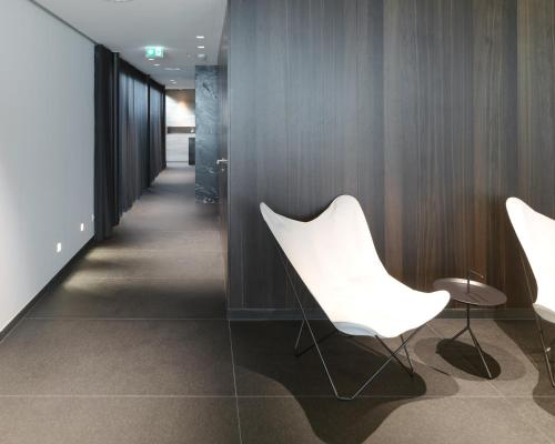 a hallway with two white chairs and wood walls at Das Flint in Dornbirn