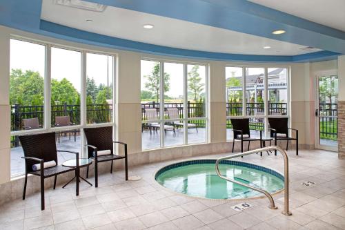 a pool in a lobby with chairs and a table at Hilton Garden Inn Toronto-Oakville in Oakville