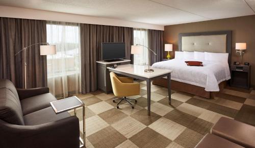 a hotel room with a bed and a desk with a television at Hampton Inn by Hilton Timmins in Timmins