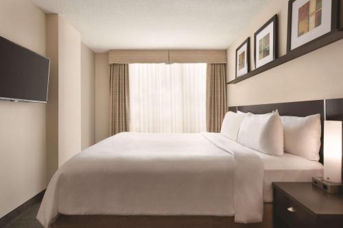 a hotel room with a large white bed and a window at Embassy Suites by Hilton - Montreal in Montréal