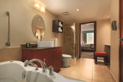 a bathroom with a sink and a toilet and a mirror at Embassy Suites by Hilton - Montreal in Montreal