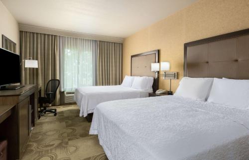 a hotel room with two beds and a flat screen tv at Hampton Inn & Suites Yuba City in Yuba City