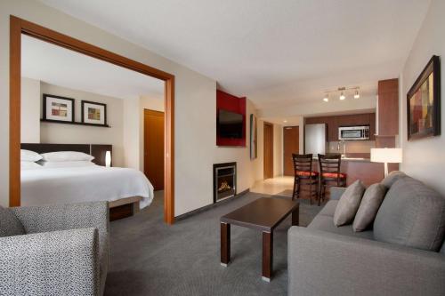 モントリオールにあるエンバシー スイーツ バイ ヒルトン - モントリオールのベッドとリビングルームが備わるホテルルームです。
