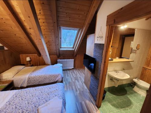 una camera con due letti e un lavandino in una stanza di Hotel Tarvisio a Tarvisio