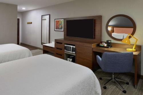 a hotel room with two beds and a desk with a television at Hampton Inn & Suites Montreal-Dorval in Dorval