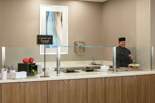a man is standing in a kitchen with a mirror at Embassy Suites By Hilton Montreal Airport in Pointe-Claire