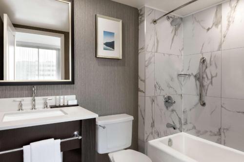 a bathroom with a toilet and a sink and a shower at Embassy Suites By Hilton Montreal Airport in Pointe-Claire