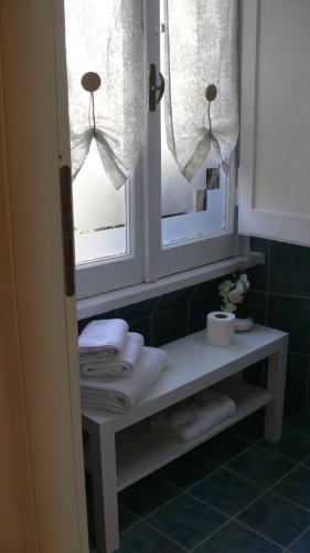 a bathroom with two windows and a shelf with towels at Camera Con Vista in Rome